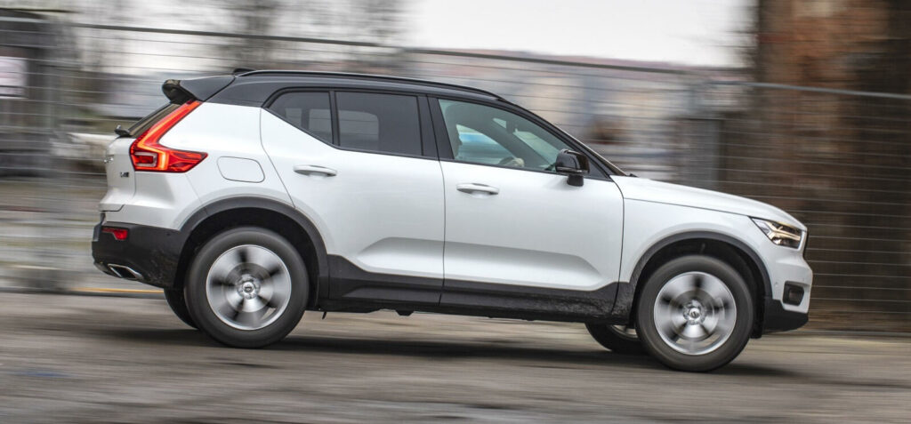 En vit Volvo XC90 SUV kör ner en väg. (AI text)