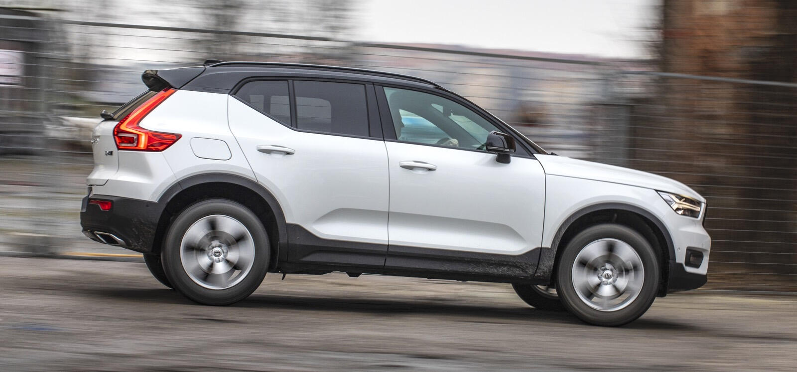 En vit Volvo XC90 SUV kör ner en väg. (AI text)