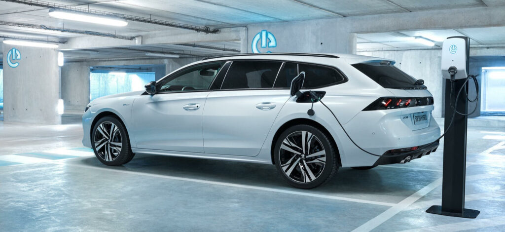 En vit bil parkerad i en elbils-uppladdningsstation. (AI text)