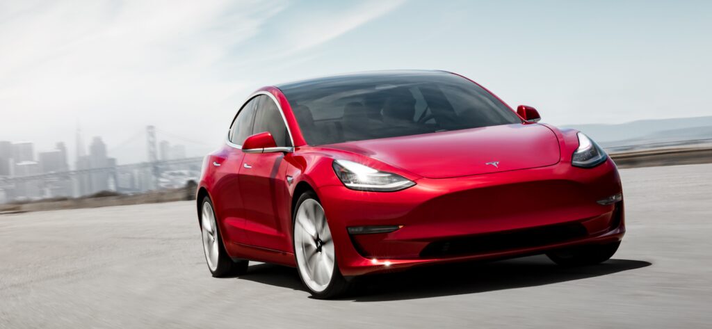 Tesla Model 3 kör på en stadsgata. (AI text)