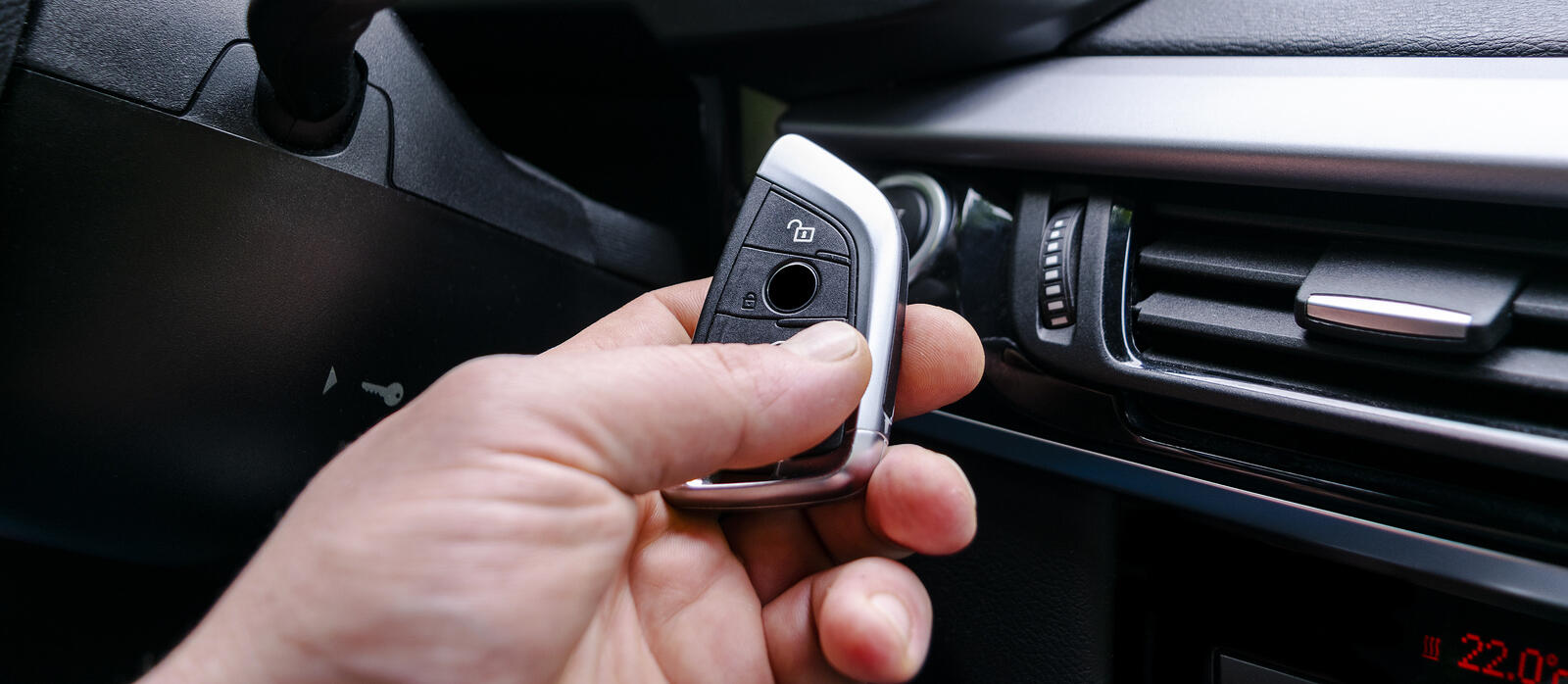 En man använder en fjärrkontroll för att öppna bilens dörre. (AI text)
