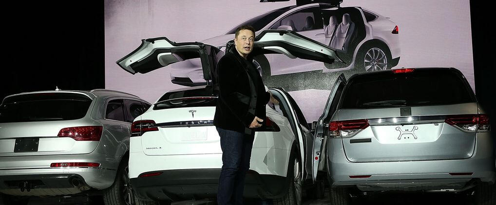 En man står bredvid en Tesla EV. (AI text)