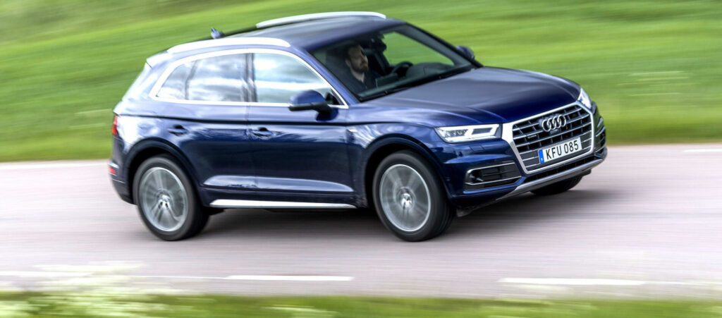 En Audi Q7 SUV kör nerför en landsväg. (AI text)