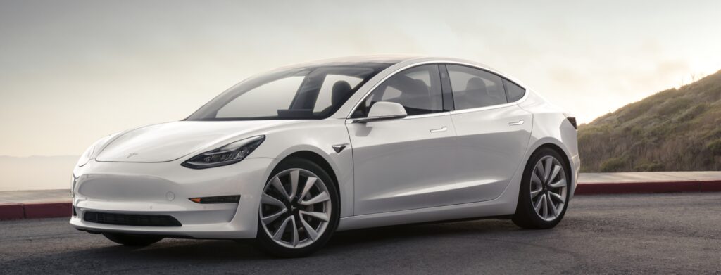 Tesla Model 3 parkerad vid kullside. (AI text)