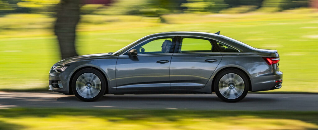 En silverfärgad Audi A6 kombi kör längs en landsväg. (AI text)