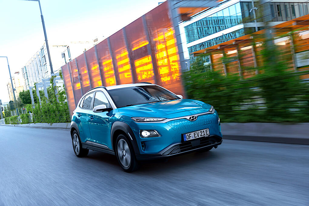 En blå Hyundai Kona kör nedför en stadsgata. (AI text)