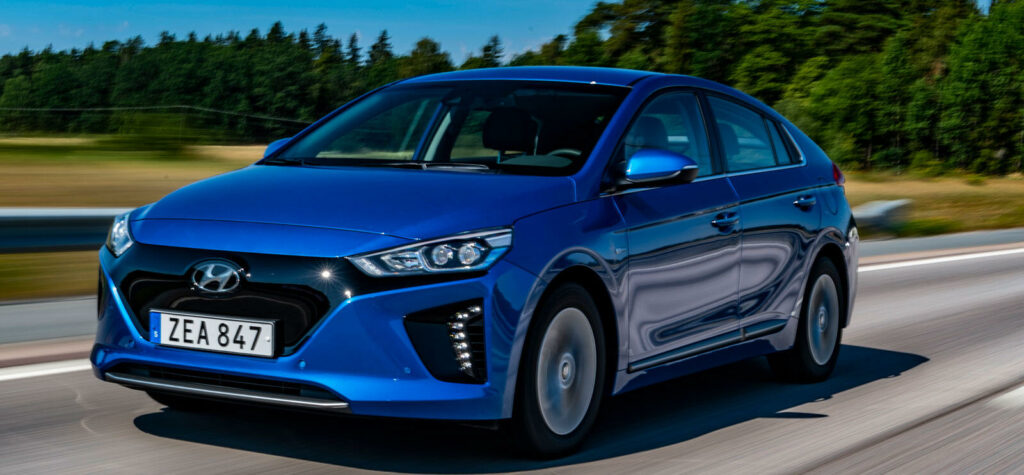 En blå Hyundai Ioniq kör nerför en landsväg. (AI text)