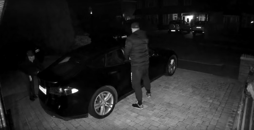 En man står bredvid en svart bil vid nattid. (AI text)