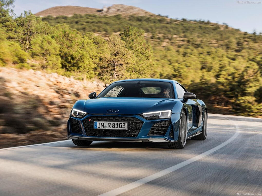 Audi R8 V10 Plus kör nedför en bergväg. (AI text)