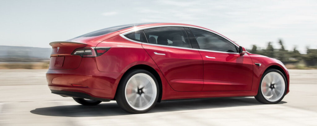 Tesla Model 3 kör på en väg. (AI text)