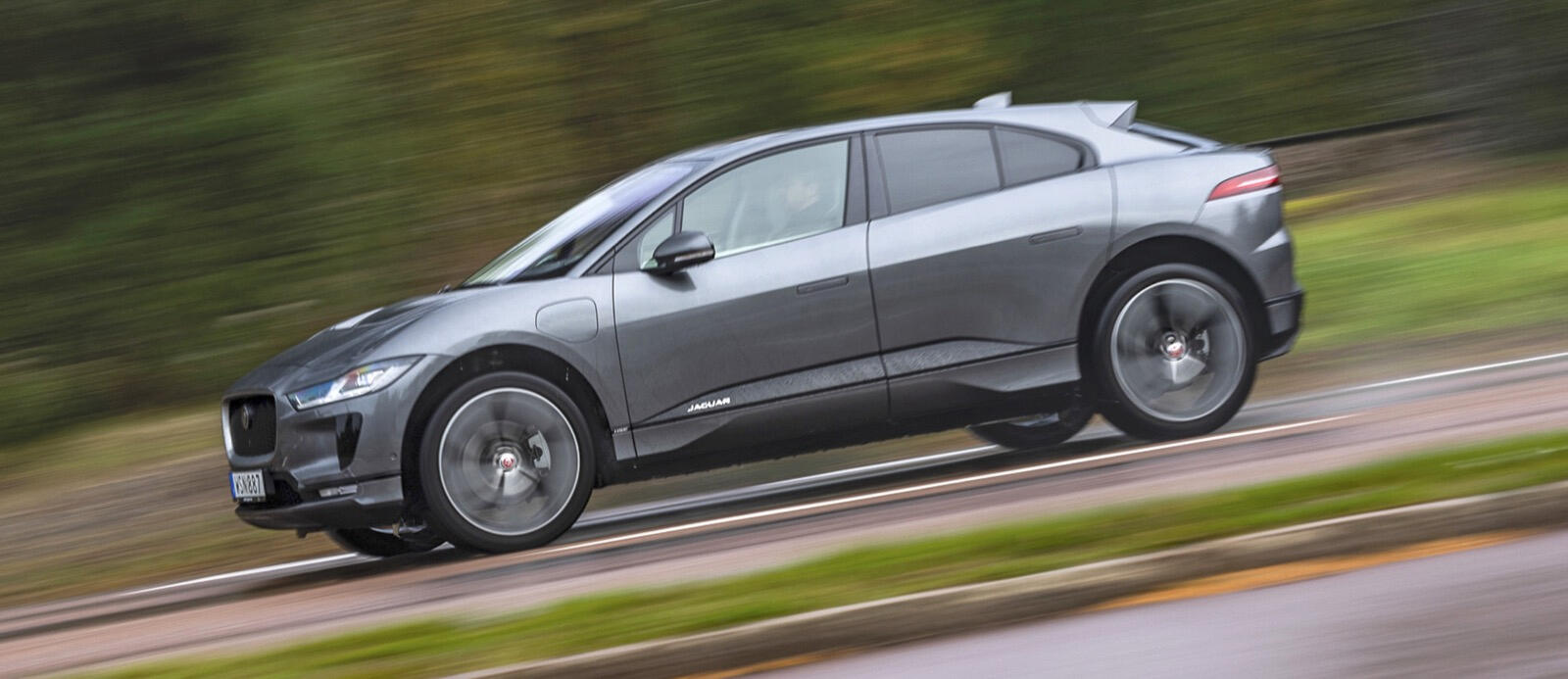En Jaguar I Pace kör nedför en landsväg. (AI text)