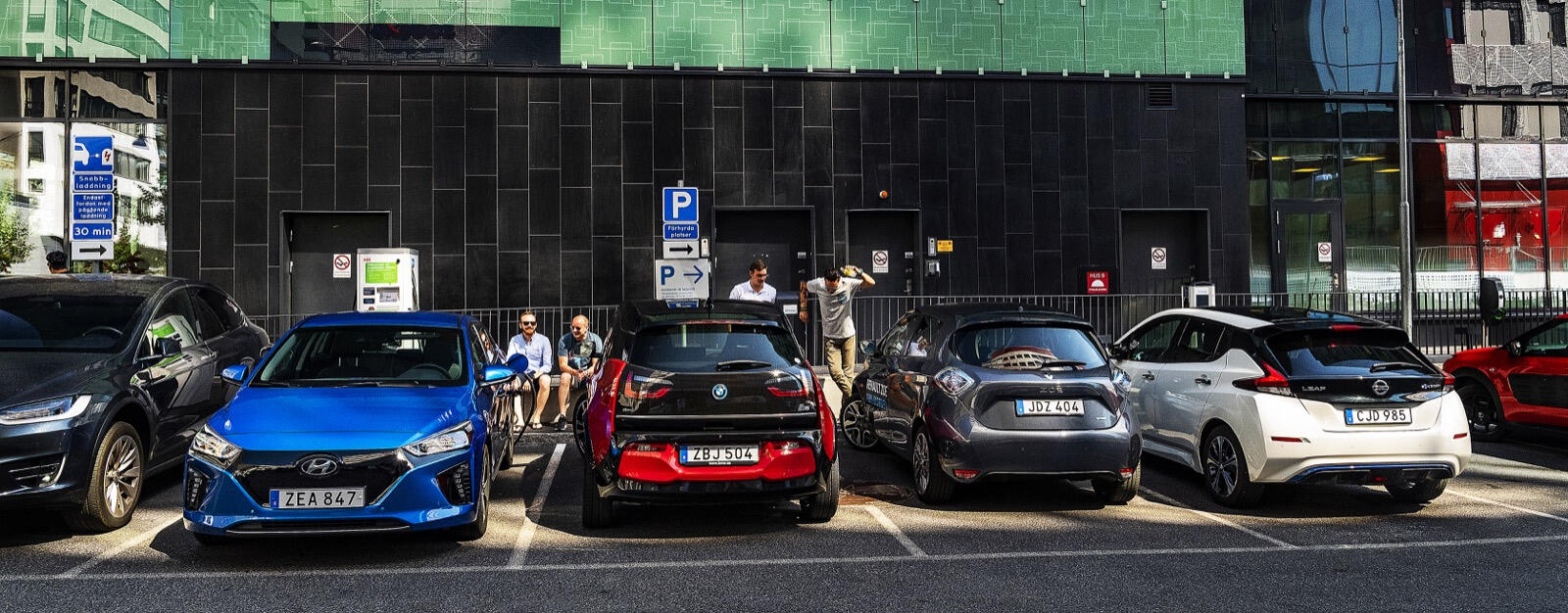 En grupp bilar parkerade framför ett byggnad. (AI text)