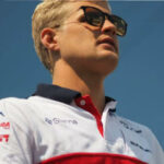 En man i ett rött och vitt skjortstånd står på en bana. (AI text)