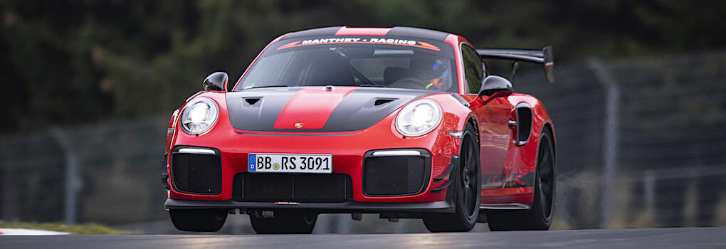 En röd Porsche 911 GT3 RS kör på en bana. (AI text)