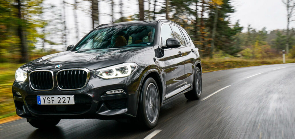 BMW X3 kör på en landsväg. (AI text)