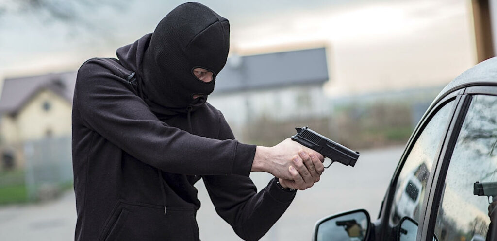En rånmisstänkt riktar en pistol mot en bil. (AI text)
