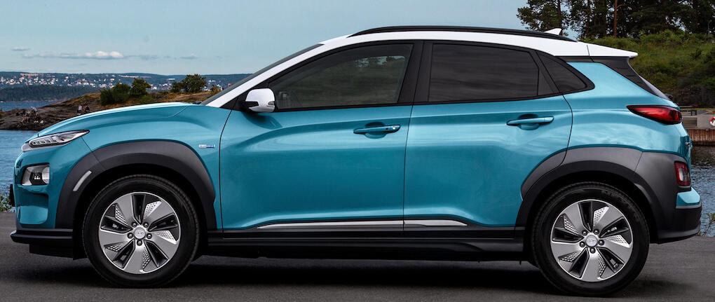 En blå Hyundai Kona parkerad på en strand. (AI text)