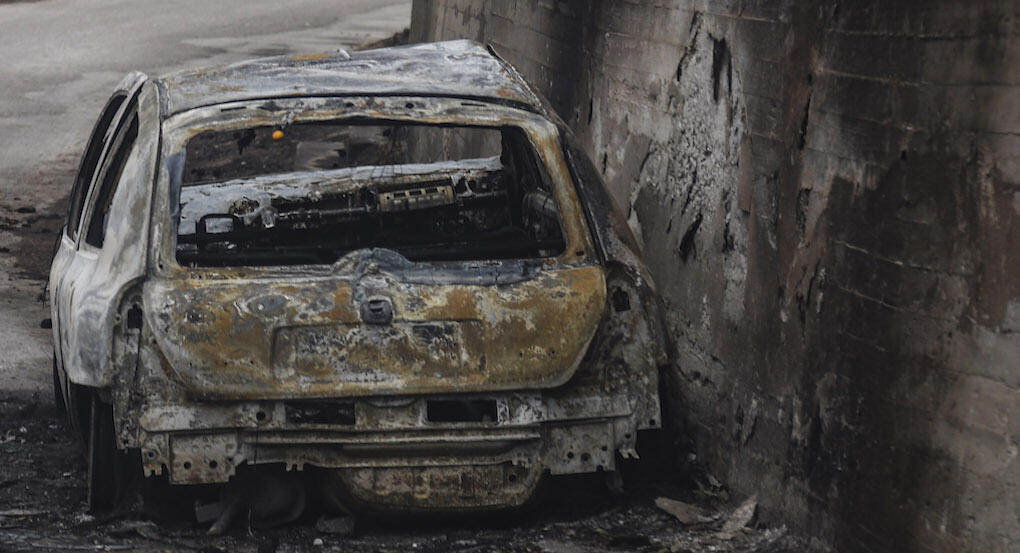 En förstörd bil står stilla på en gata. (AI text)