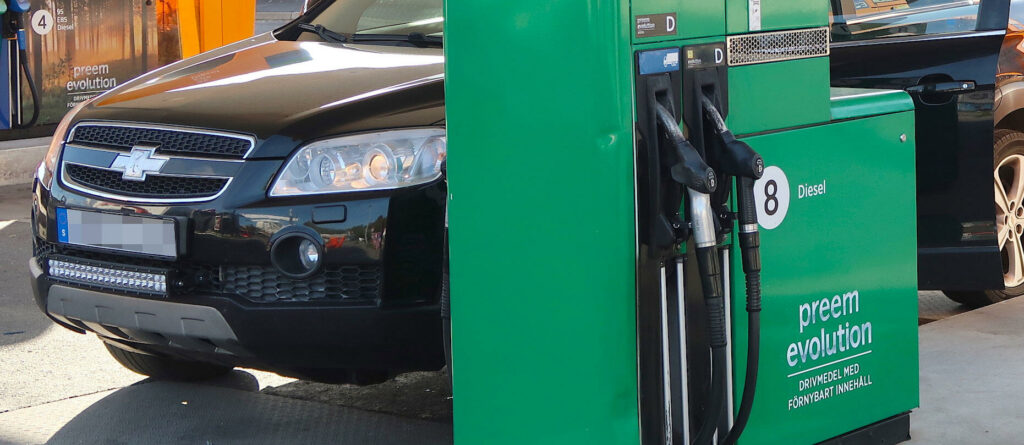 En grön bil står parkerad vid en bensinstation. (AI text)