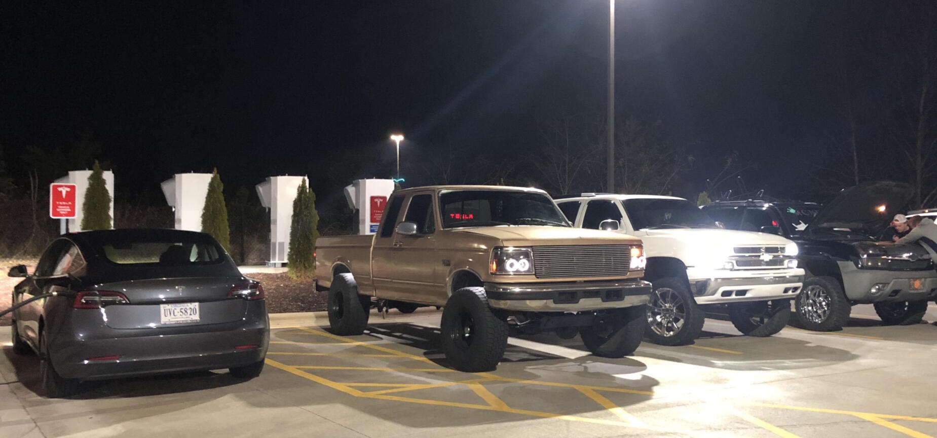 En grupp bilar parkerade i en parkeringsplats på natten. (AI text)