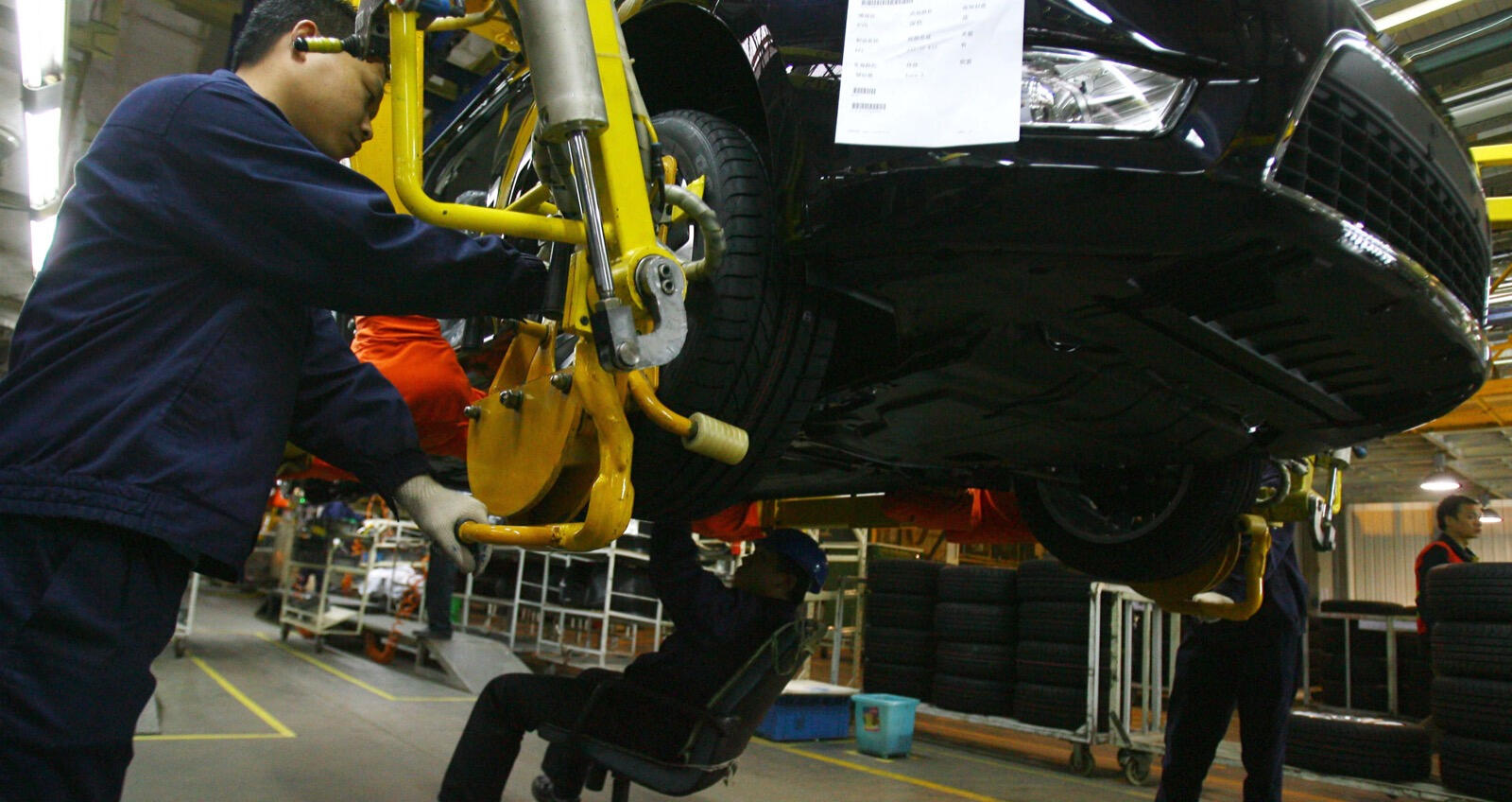 En arbetare arbetar på en bil på en fabrik. (Foto: Reuters) (AI text)