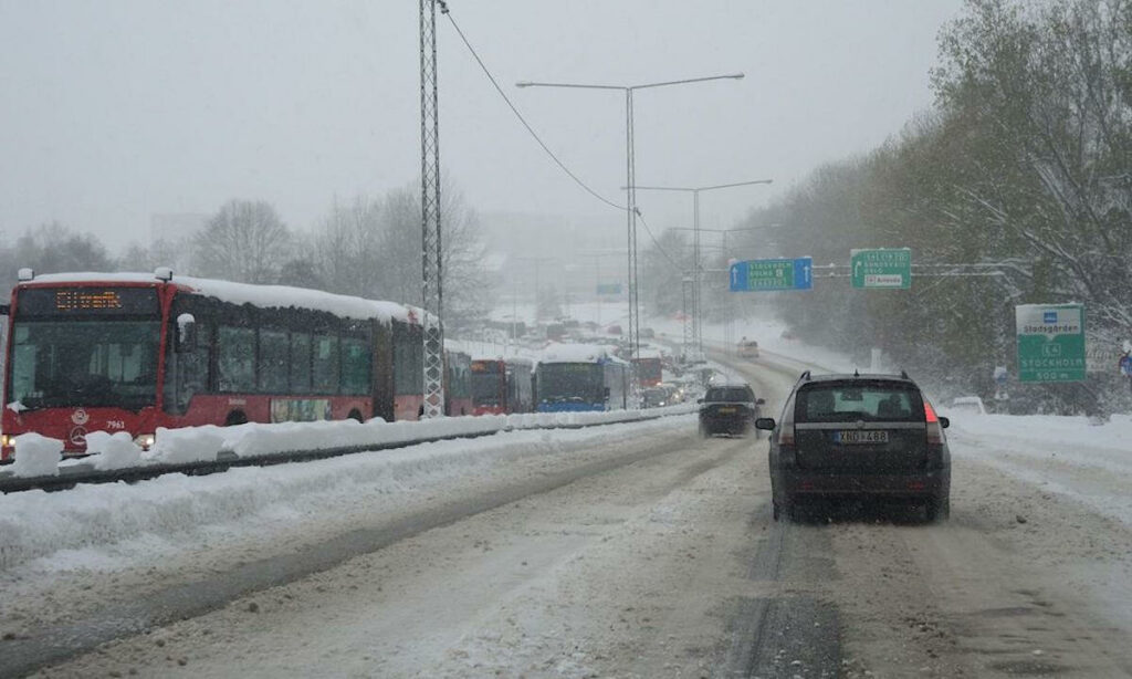 En bil kör nerför en snöig väg. (AI text)