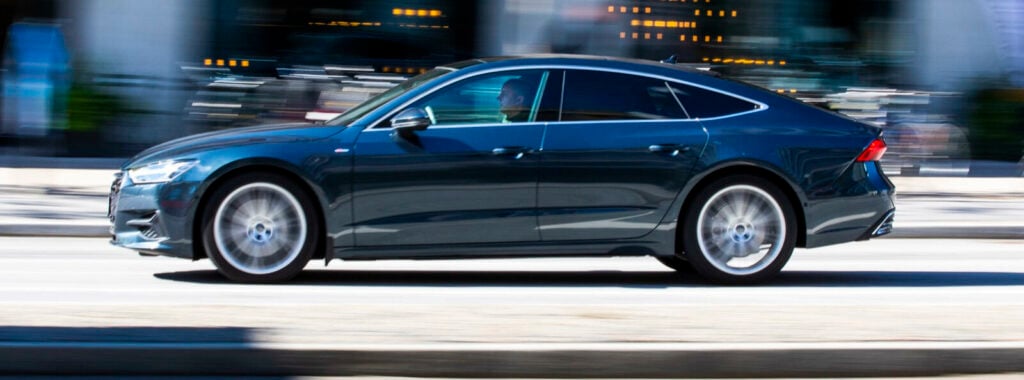 En Audi A6 sedan kör ner gatan. (AI text)