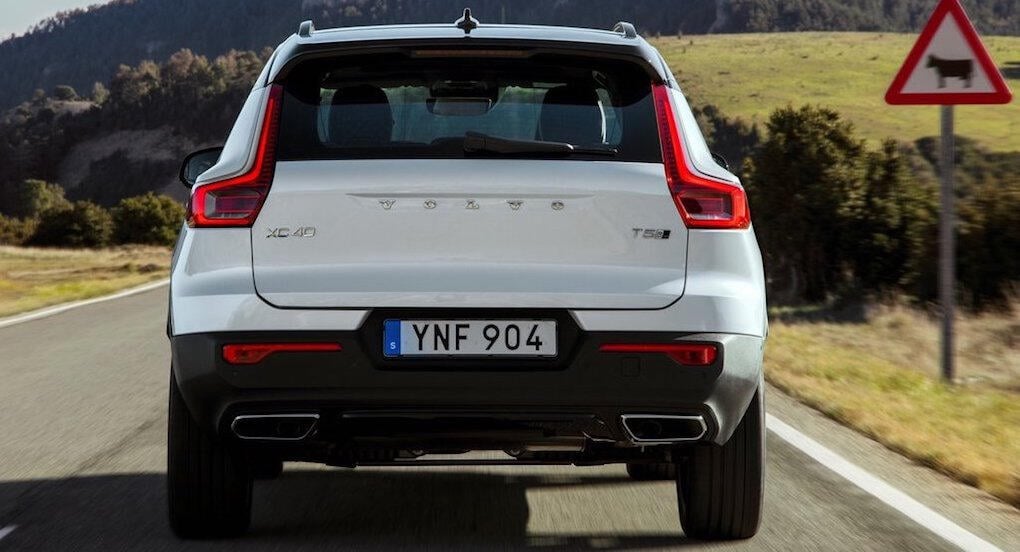 En vit Volvo XC90 SUV kör nedför en landsväg. (AI text)