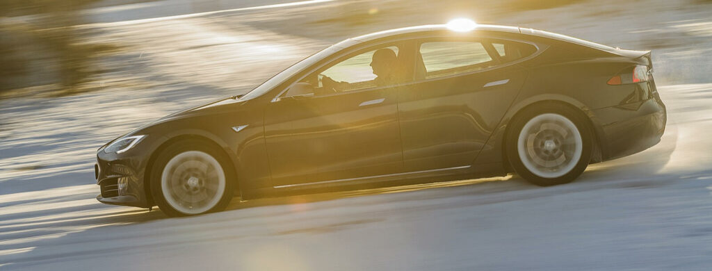 Tesla Model S kör på snöig väg. (AI text)