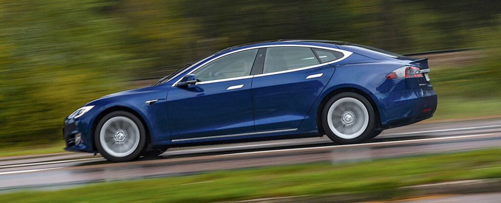 En Tesla Model S kör nedför en väg. (AI text)