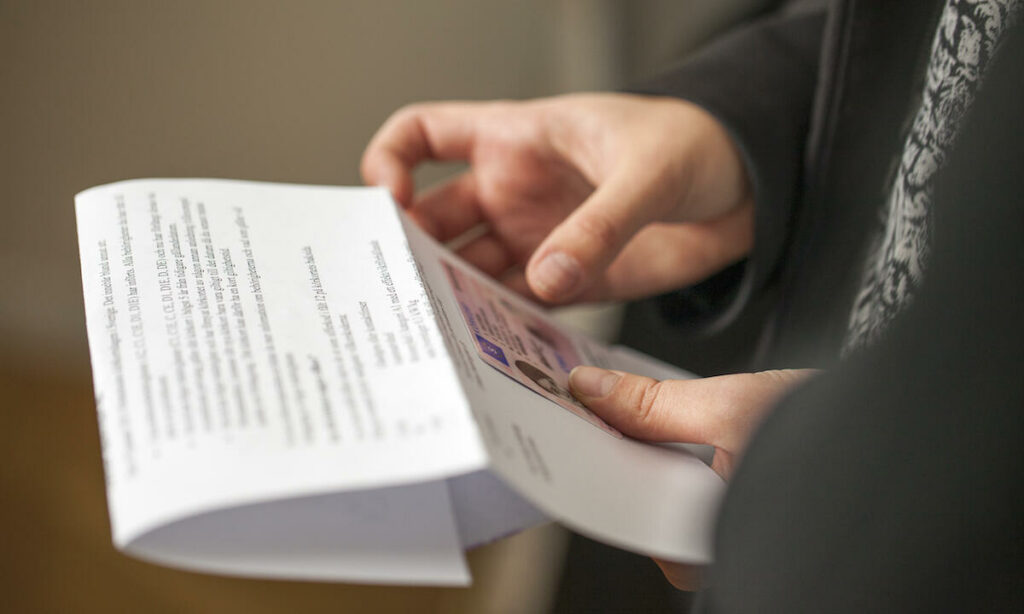 En person håller ett papper framför en bil. (AI text)