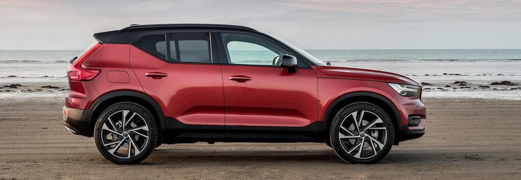 En röd Volvo XC90 parkerad på en strand. (AI text)