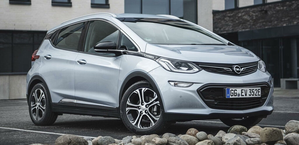 En silverfärgad Opel ECV parkerad framför ett byggnad. (AI text)