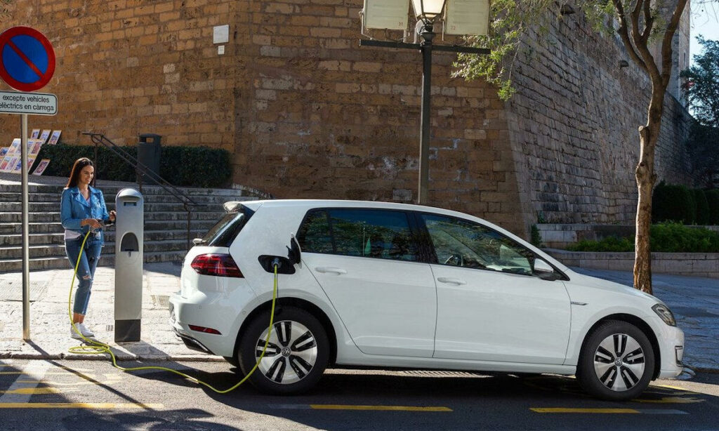 En kvinna laddar sin bil vid en elbilsladdstation. (AI text)