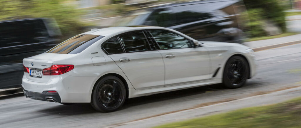 BMW 5-serie sedan kör på vägen (AI text)