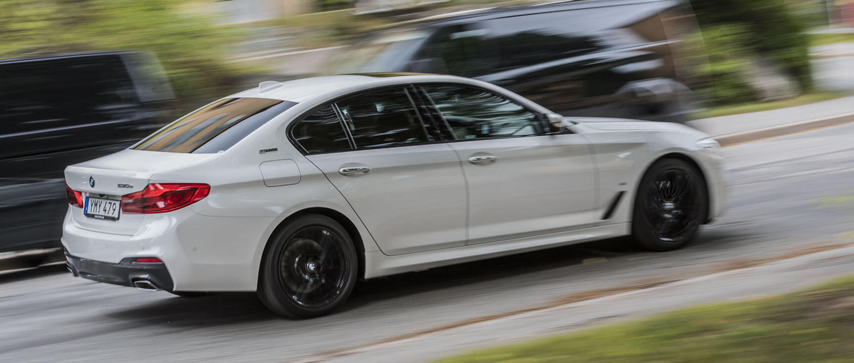 BMW 5-serie sedan kör på vägen (AI text)