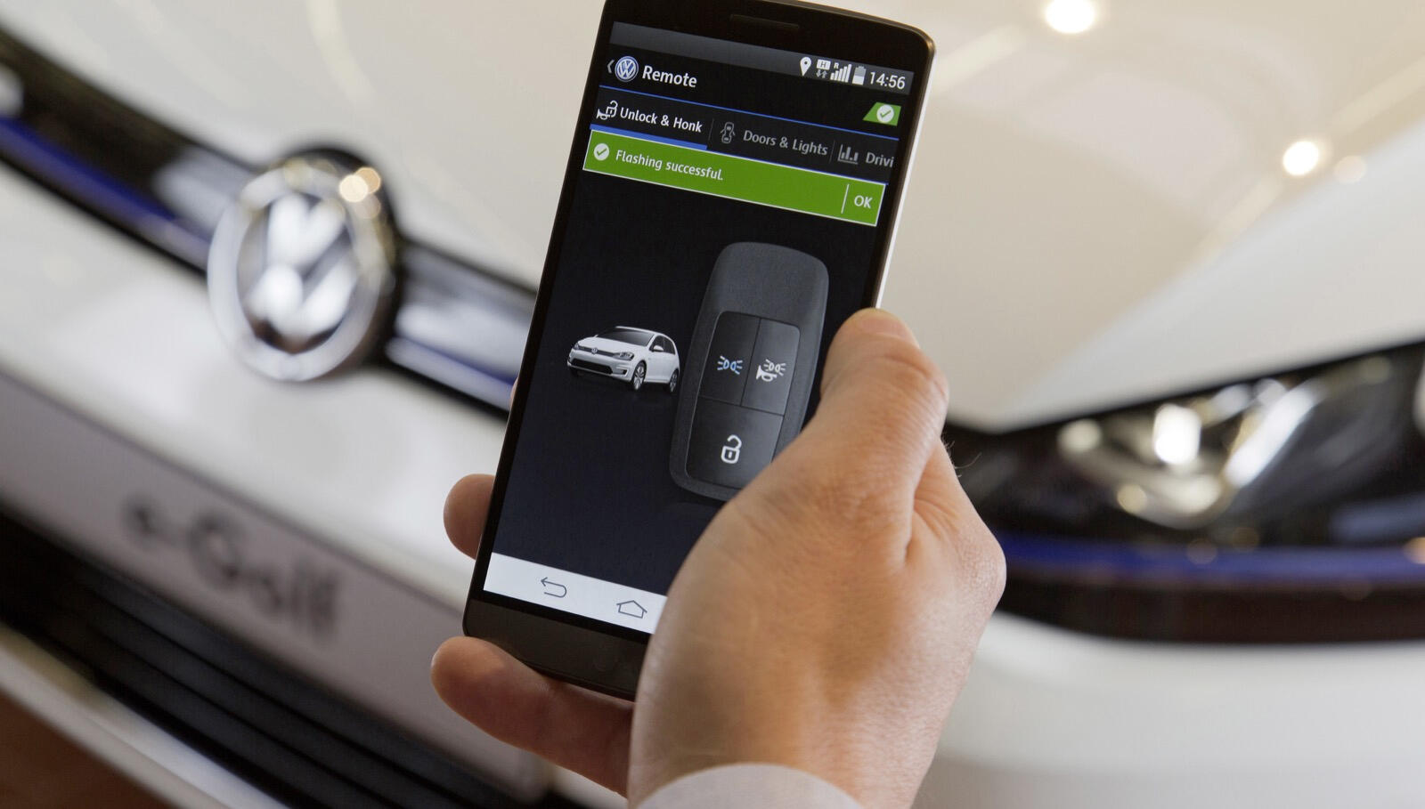 En person håller ett smartphone medan de tittar på en Volkswagen e-Golf. (AI text)