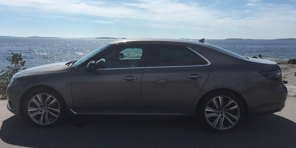 En bil parkerad vid en väg nära havet. (AI text)