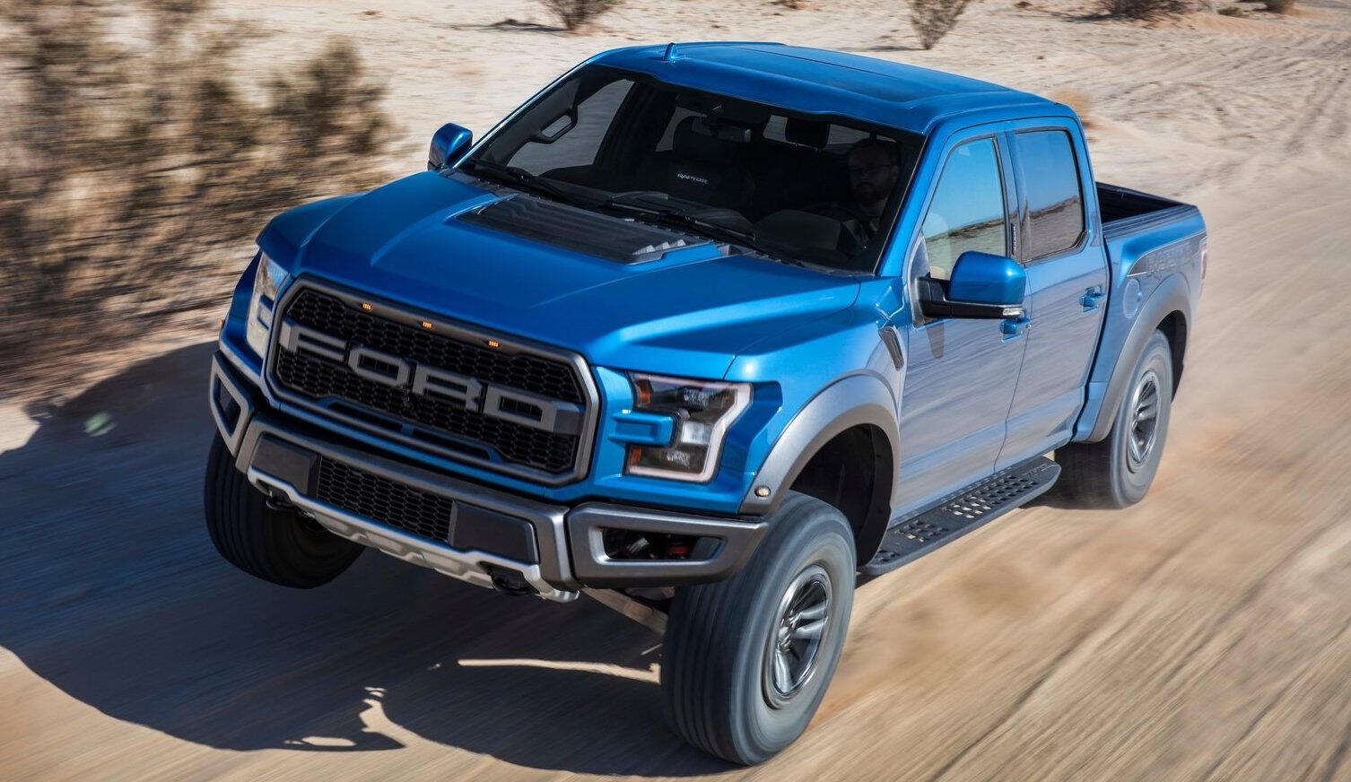 Den 2019 års Ford F-150 Raptor kör längs en ökenväg. (AI text)