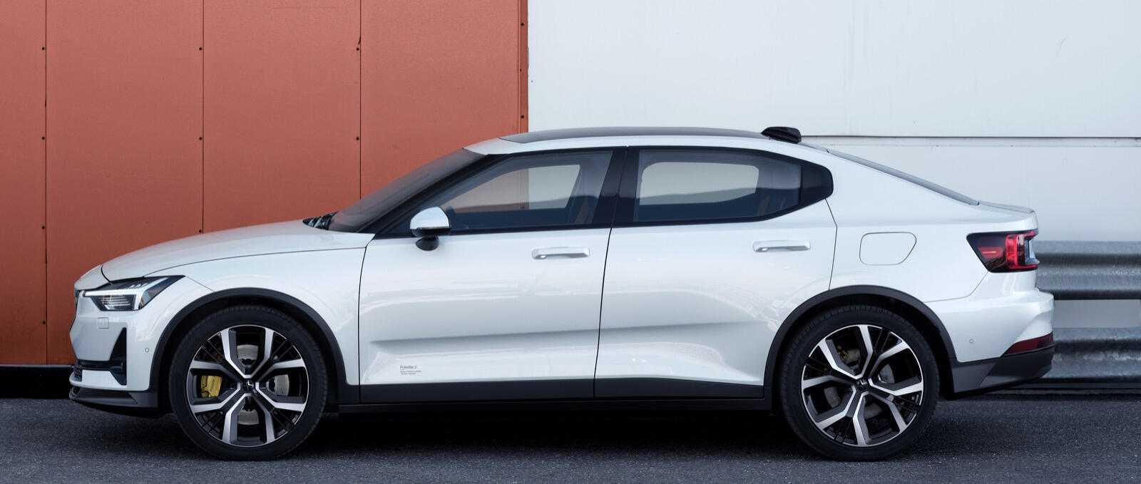 En vit Volvo V40 eV parkerad framför ett byggnad. (AI text)