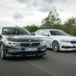 Två BMW 5-serie-sedaner kör längs en landsväg. (AI text)
