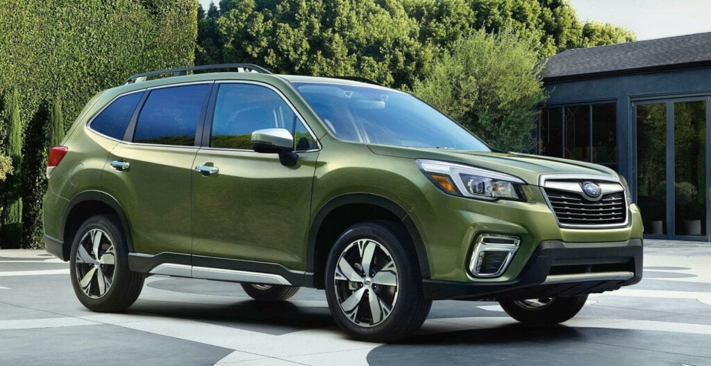 En grön Subaru Forester parkerad framför ett hus. (AI text)