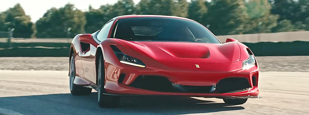 En röd Ferrari-sportbil kör längs en bana. (AI text)