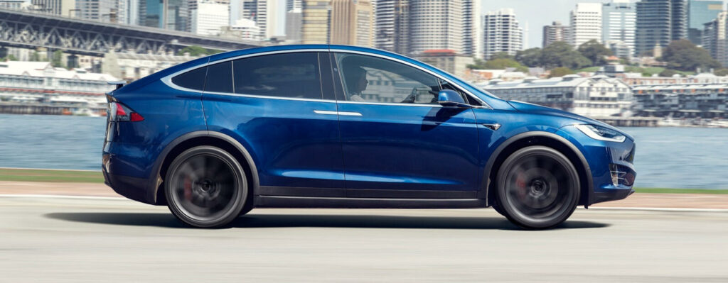 Tesla Model X kör på en stadsgata. (AI text)