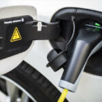 En vit bil är uppkopplad till en elbilsladdare. (AI text)