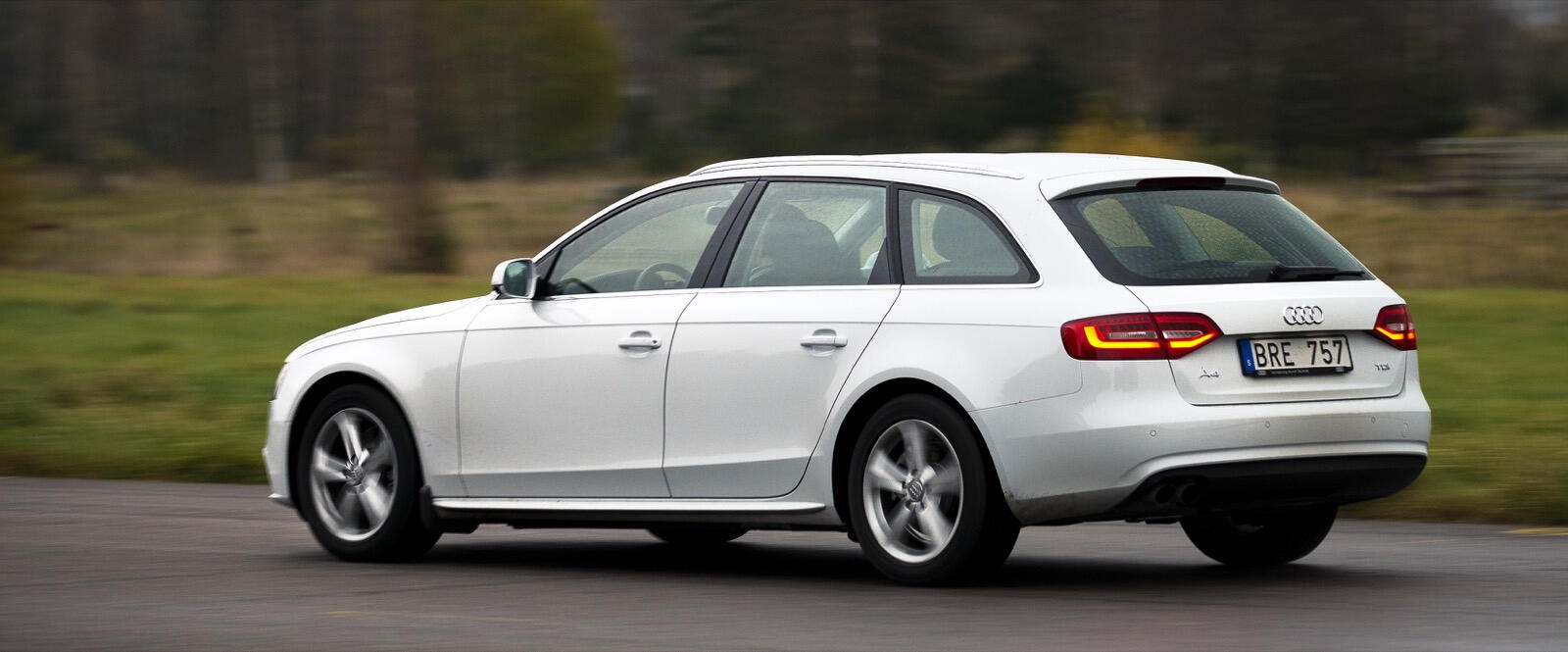 En Audi A4 kombi kör längs en landsväg. (AI text)