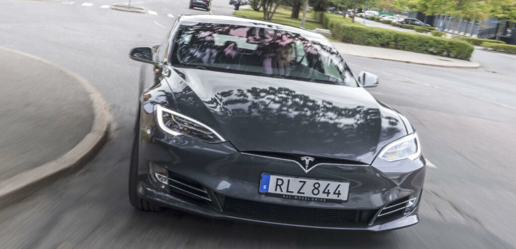 Tesla Model S kör på en stadsgata. (AI text)