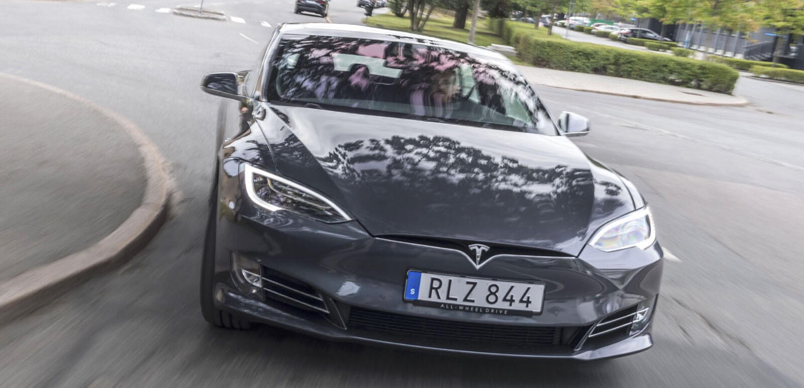 Tesla Model S kör på en stadsgata. (AI text)
