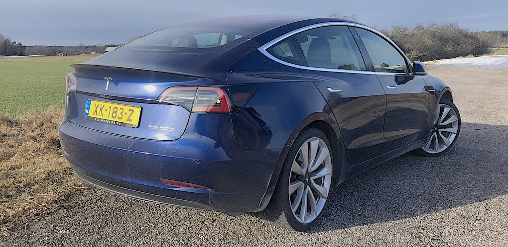 Tesla Model 3 parkerad på grusväg (AI text)