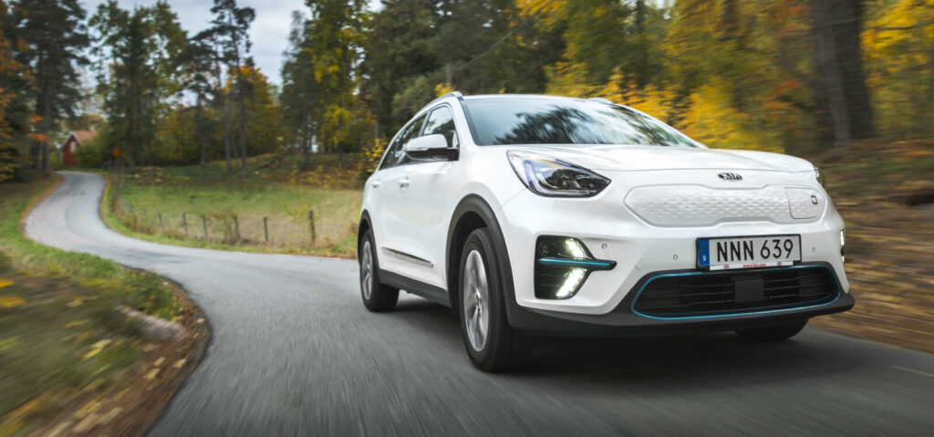 En vit Kia Soul kör nerför en landsväg. (AI text)